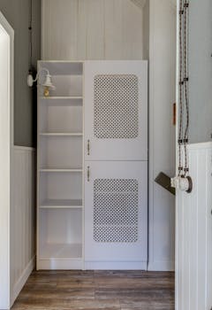 Simple white cabinet with shelves and patterned doors in a tidy indoor setting.
